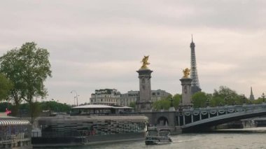 PARIS, FRANCE - 21 NİSAN 2025: Seine Nehri manzarası, set seti, tek kemerli köprü Pont Alexandre III, Eyfel Kulesi ve akşam gökyüzüne doğru giden bir tekne..