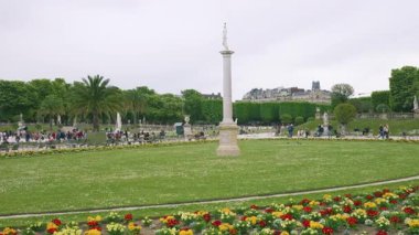 Lüksemburg Sarayı, Büyük Havza 'nın panoramik manzarası, yeşil metal koltuklarda dinlenen turistler ve Lüksemburg Bahçesi' nde güneşli bir bahar gününde 6. bölgede gezinen turistler, Paris, Fransa.