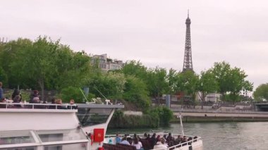 PARIS, FRANCE - 21 NİSAN 2025: Eyfel Kulesi manzarası ve yanından geçen turistlerle dolu çift katlı bir tekne..