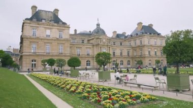 PARIS, FRANCE - 21 Nisan 2025: Lüksemburg Sarayı manzarası, ilkbahar Primula yatakları ve turistler. Lüksemburg Bahçeleri, 6. Bölge, Paris.