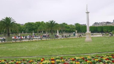 PARIS, FRANCE - 21 Nisan 2025: Lüksemburg Sarayı, Büyük Havza 'nın panoramik manzarası, turistler yeşil metal koltuklarda dinleniyor ve güneşli bir bahar gününde Lüksemburg Bahçesi' nde geziniyorlar..