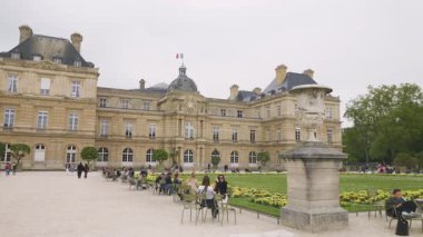 PARIS, FRANCE - 21 Nisan 2025: Lüksemburg Sarayı, Büyük Havza 'nın panoramik manzarası, turistler yeşil metal koltuklarda dinleniyor ve güneşli bir bahar gününde Lüksemburg Bahçesi' nde geziniyorlar..