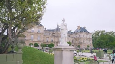 PARIS, FRANCE - 21 Nisan 2025: Turistler baharda Lüksemburg Bahçeleri 'nde yürürken, Minerva heykeli ve Lüksemburg Sarayı manzarası, Paris' in 6..