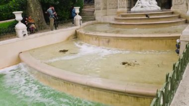 PARIS, FRANCE - 21 Nisan 2025: İnsanlar 6. Paris 'teki Lüksemburg Bahçeleri' ndeki Medici Çeşmesi yakınlarında hayranlık duyuyorlar ve fotoğraf çekiyorlar. Barok çeşmesi, Polyphemus 'un şaşırtıcı Acis ve Galatea' nın mitolojik sahnesini tasvir ediyor..