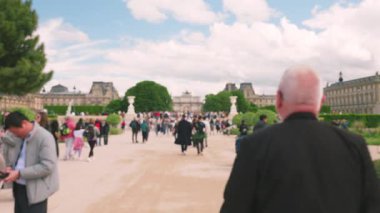 Fransa 'nın başkenti Paris' te açık bir günde arka planda Louvre ile birlikte turist kalabalığı Tuileries Parkı 'nda geziniyor. Odaklanamıyorum.