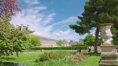 Baharda, çiçek açan ağaçlar, çiçek tarlaları ve Louvre manzaralı Tuileries Bahçesi. Tuileries Park, Paris, Fransa 'da yürüyen ve dinlenen insanlar.
