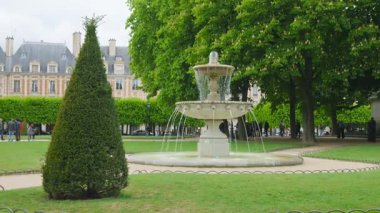 Cortot 'un dört çeşmesinden biri Place des Vosges' un köşelerine eski tarihi binalara ve Fransa 'nın Paris şehrinde filizlenen kestane ağaçlarına karşı kurulmuş..