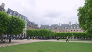 Ihlamur yataklarının panoramik manzarası, Cortot çeşmeleri, satılan binalar ve yürüyen insanlar Place des Vosges, Paris, Fransa.