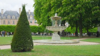 PARIS, FRANCE - 19 Nisan 2025: Cortot 'un dört çeşmesinden biri Vosges Meydanı' nın köşelerine eski tarihi binalara ve Fransa 'nın Paris kentinde filizlenen uzun kestane ağaçlarına karşı kurulmuş..