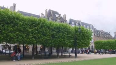 PARIS, FRANCE - 19 Nisan 2025: Ihlamur, Cortot çeşmeleri, eski binalar ve Vosges Meydanı 'nda yürüyen insanların panoramik manzarası.