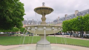 PARIS, FRANCE - 19 Nisan 2025: Eski tarihi yapılara karşı Place des Vosges 'un köşelerine kurulmuş dört çeşmeden biri.