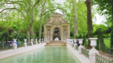 Medici Çeşmesi 'nin genel manzarası ve Lüksemburg Bahçeleri' nde güneşli bir bahar gününde çevreleyen yeşil ağaçlarla çevrili turistler. 6. Bölge, Paris. Odaklanamıyorum. Paris, Fransa.