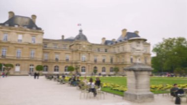 Lüksemburg Sarayı, Büyük Havza 'nın panoramik manzarası, yeşil metal koltuklarda dinlenen turistler ve Paris' in 6. semtinde güneşli bir bahar gününde Lüksemburg Bahçesinde gezinen turistler. Odaklanamıyorum. Paris, Fransa.