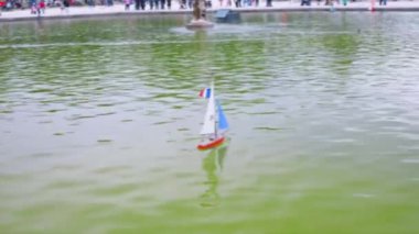 Fransa bayrağı direkte, Lüksemburg Bahçeleri 'ndeki Büyük Havza' da beyaz ve mavi yelkenli model bir yelkenli. Paris, Fransa. Odaklanamıyorum.