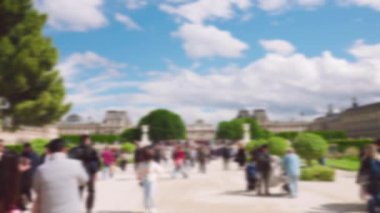 Turist kalabalığı baharda Tuileries Parkı 'nda dolaşır ve açık bir günde arka planda Louvre ile fotoğraf çekerler. Paris, Fransa. Odaklanamıyorum.