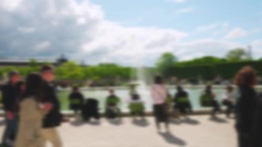 İnsanlar yeşil metal sandalyeli büyük bir havuz etrafında oturur ve güneşli bir bahar gününde parkın, Louvre 'un ve Eyfel Kulesinin manzarasının tadını çıkarırlar. Paris, Fransa. Odaklanamıyorum.