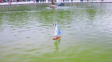 Fransa bayrağı direkte, Lüksemburg Bahçeleri 'ndeki Büyük Havza' da beyaz ve mavi yelkenli model bir yelkenli. Paris, Fransa. Odaklanamıyorum.