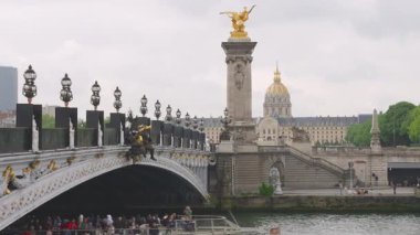Seine Nehri üzerindeki Pont Alexandre III köprüsü, turistlerle dolu çift güverte feribotu ve Fransa 'nın başkenti Paris' te bulunan Invalides Evi manzarası..