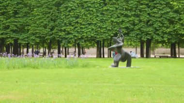 La Grande Musicienne heykeli çimenliğin yeşil çimlerinde Jardin des Tuileries 'de (Tuileries Bahçesi) budanmış ağaçların arka planında 1. bölgede bulutlu bir bahar günü, Paris, Fransa.