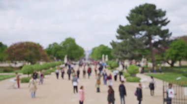 Güneşli bir bahar günü, Fransa 'nın başkenti Paris' te, Jardin des Tuileries Bahçesi 'nde (Tuileries Garden) insanlar ana cadde boyunca yürürler. Odaklanamıyorum. Yavaş çekim.