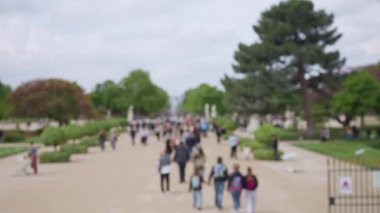 Güneşli bir bahar günü, Fransa 'nın başkenti Paris' te, Jardin des Tuileries Bahçesi 'nde (Tuileries Garden) insanlar ana cadde boyunca yürürler. Odaklanamıyorum. Yavaş çekim.