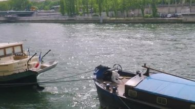 PARIS, FRANCE - 21 Nisan 2025: Seine Nehri 'nin sağ kıyısına demirlemiş motorlu teknelerin ve bahar kulesinin manzarası.