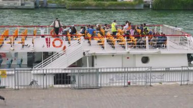 PARIS, FRANCE - 21 Nisan 2025: İnsanlar Seine Nehri boyunca giden çift katlı bir feribot gibi turistik bir feribotun üst güvertesindeki koltuklarına oturuyorlar..