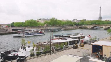 PARIS, FRANCE - 21 Nisan 2025: Seine Nehri 'nin sol kıyısındaki Eyfel Kulesi' nin manzarası, set, feribot ve botlar.