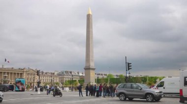 PARIS, FRANCE - 21 Nisan 2025: Birinci bölgedeki bulutlu bir bahar gününde arka planda Obelisque de Louxor ve Jardin des Tuileries manzaralı Concorde Meydanı 'ndan geçen yaya trafiği.