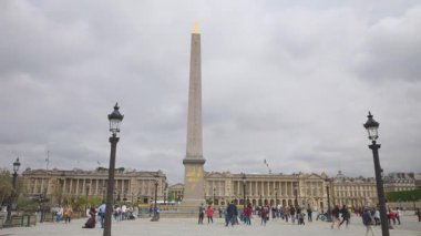 PARİS, FRANCE - 21 Nisan 2025: Birinci bölgedeki bulutlu bir ilkbahar gününde Obelisque de Louxor ve Hotel de la Marine manzaralı Concorde Meydanı 'nda gezinen insanlar.