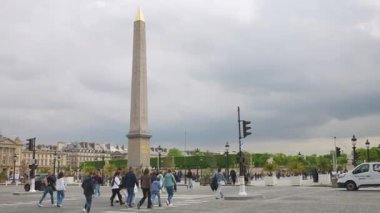 PARIS, FRANCE - 21 Nisan 2025: Birinci bölgedeki bulutlu bir bahar gününde Obelisque de Louxor ve Jardin des Tuileries manzaralı Concorde Meydanı üzerinde yaya geçidi boyunca yürüyenler.
