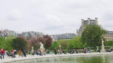 PARIS, FRANCE - 21 Nisan 2025: Birinci bölgede bulutlu bir ilkbahar gününde, Jardin des Tuileries Bahçesi 'ndeki Büyük Basin Rond (Büyük yuvarlak havuz) etrafında yürüyen ve rahatlayan insanlar.