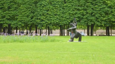 PARIS, FRANCE - 21 Nisan 2025: 1. bölgedeki bulutlu bir bahar gününde, Jardin des Tuileries 'deki (Tuileries Garden) budanmış ağaçların arka planına karşı çimlerin üzerindeki La Grande Musicienne heykeli.
