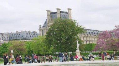 PARIS, FRANCE - 21 Nisan 2025: Birinci bölgede bulutlu bir ilkbahar gününde, Jardin des Tuileries Bahçesi 'ndeki Büyük Basin Rond (Büyük yuvarlak havuz) etrafında yürüyen ve rahatlayan insanlar.