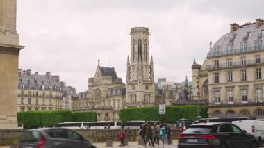 PARIS, FRANCE - 21 Nisan 2025 Quai Francois Mitterrand 'ın karşısındaki Saint-Germain l' Auxerrois Kilisesi bulutlu bir ilkbahar gününde yoğun bir trafik ile.