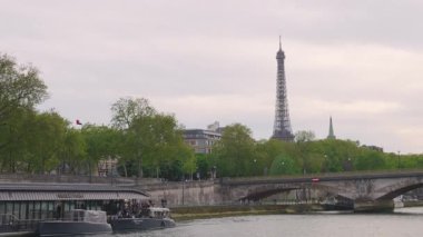 PARIS, FRANCE - 21 Nisan 2025 Seine Nehri 'nde gezinti. Seine Nehri 'nin güvertesinden, Pont des Invalides' ten ve Eiffel Kulesi 'nden bulutlu bir akşamda görüntüyü izleyin..