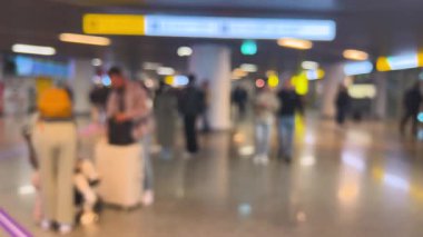 İnsanlar havaalanının bekleme alanının etrafında dolanıyor. Odaklanamıyorum.