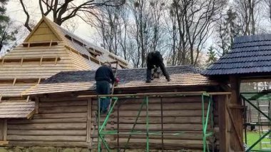 Erkekler ahşap kiremitleri nemden korumak için siyah, ham yağ bazlı bir bileşikle kaplarlar..