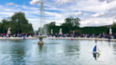 İnsanlar Grand Bassin Rond (Büyük yuvarlak havuz) çevresinde oturur ve rahatlarlar, Jardin des Tuileries 'de küçük yelkenli modelleri yüzer, 1. bölgede. Odaklanamıyorum. Paris, Fransa.