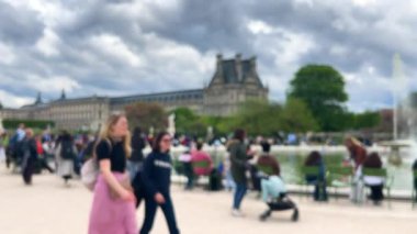 Birinci arrondissement 'te bulutlu bir bahar gününde Jardin des Tuileries' de (Tuileries Garden) insanlar Grand Bassin Rond (Büyük yuvarlak havuz) etrafında yürüyüp rahatlıyorlar. Odaklanamıyorum. Paris, Fransa.
