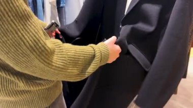 Kız düğmelerini açtı, elbise askısını çıkardı ve lüks Fransız mağazası Galeries Lafayette Haussmann, Paris, Fransa 'da siyah yün ceketi denedi..