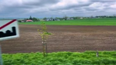 Resimli Polonya tarlalarının, bulutlu gökyüzünün altındaki köylerin otobüs penceresinden bak.