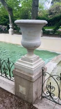 PARIS, FRANCE - 21 Nisan 2025: Medici Çeşmesi 'nin genel manzarası ve Lüksemburg Bahçeleri' ndeki yeşil ağaçlarla çevrili turistler güneşli bir bahar günü, 6. arrondissement.