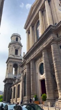 PARIS, FRANCE - 21 Nisan 2025: 6. Bölge 'de sokaklarda yürüyüş. Saint-Sulpice Kilisesi manzarası. Dikey video.