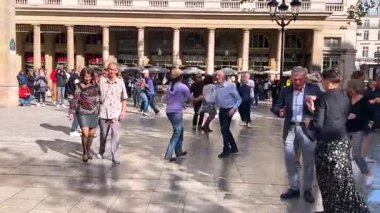 PARIS, FRANCE - 21 Nisan 2025: Place Colette 'te sokak dansçıları güneşli bir bahar akşamında Palais Royal ve Comedie-Francaise tiyatrosu arasında yer alırlar..
