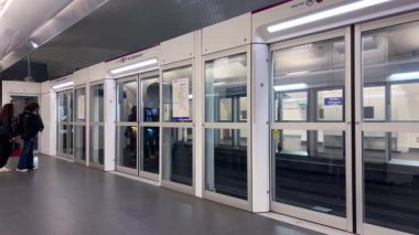PARIS, FRANCE - 21 Nisan 2025: Denfert-Rochereau modern metro istasyonuna tren geliyor, tren kapılarıyla aynı anda açılan otomatik kapıları olan şeffaf bariyerlerle kaplı..