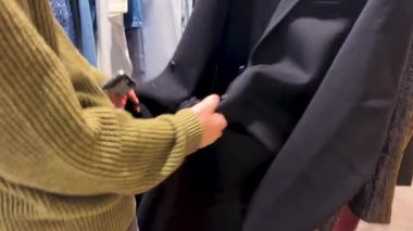 PARIS, FRANCE - 21 Nisan 2025: Kız düğmelerini açtı, elbise askısını çıkardı ve lüks Fransız mağazası Galeries Lafayette Haussmann 'daki siyah yün ceketi denedi.