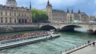 PARIS, FRANCE - 21 Nisan 2025: Turistlerle dolu büyük çift katlı feribot, Seine Nehri üzerindeki Pont au Change köprüsü, Quai de l 'Horloge seti, Paris Mahkemesi binaları.