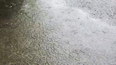 Yağmur sırasında yağmur birikintisi. Düşen yağmur damlalarından dolayı suyun üzerinde daireler çizer.