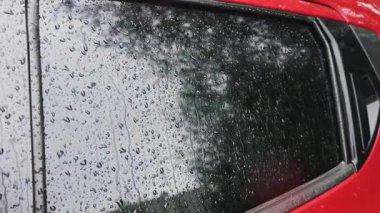 Yağmur sırasında su damlaları bir arabanın yan camından aşağı yuvarlanır..